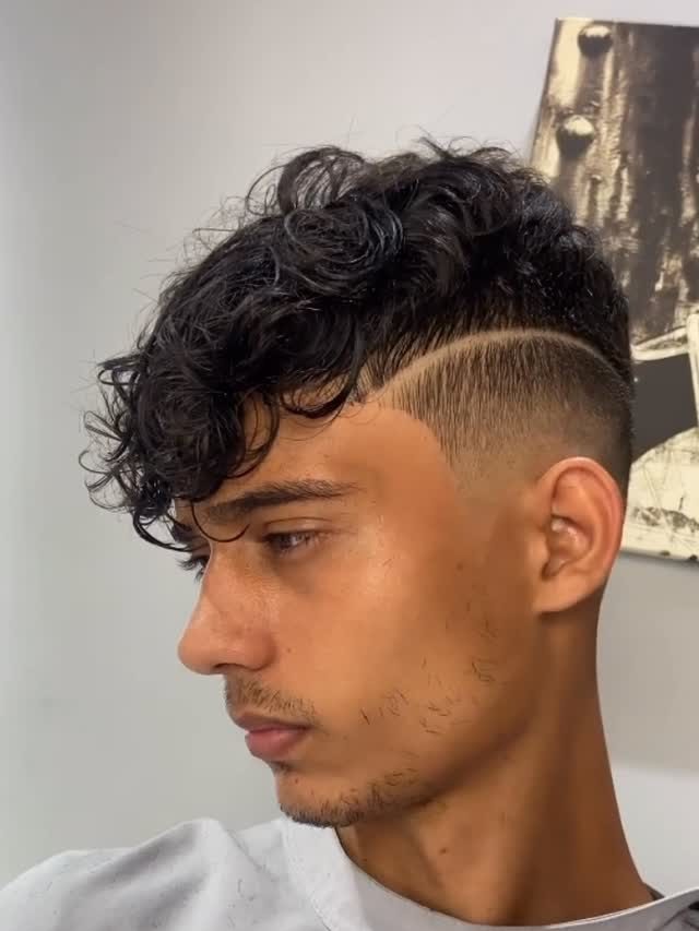 Corte com cachos no topo, degradê e risco lateral